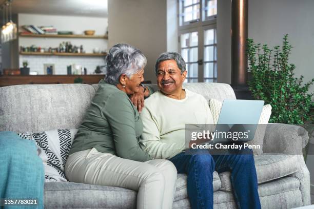 scatto di una coppia di anziani che usa un laptop sul divano di casa - coppia anziana foto e immagini stock