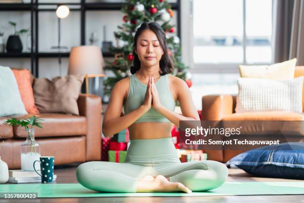 happiness healthy asian female woman in yoga work out cloth doing yoga exercise against christmas tree,asian female woman spending christmas holiday morning time do yoga workout in living room at home morning activity healthy lifestyle - yoga ball work 個照片及圖片檔
