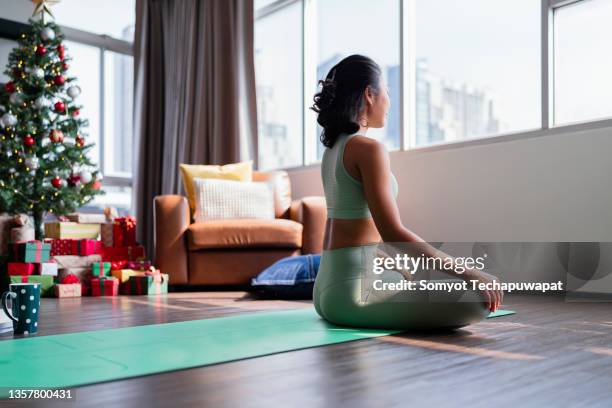 happiness healthy asian female woman in yoga work out cloth doing yoga exercise against christmas tree,asian female woman spending christmas holiday morning time do yoga workout in living room at home morning activity healthy lifestyle - winter sport stock-fotos und bilder