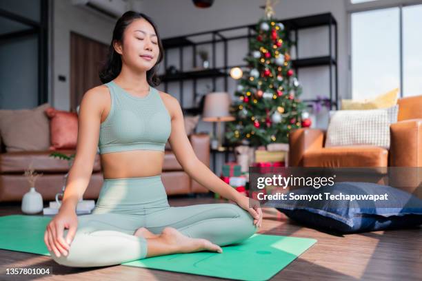 happiness healthy asian female woman in yoga work out cloth doing yoga exercise against christmas tree,asian female woman spending christmas holiday morning time do yoga workout in living room at home morning activity healthy lifestyle - breathing new life stock pictures, royalty-free photos & images