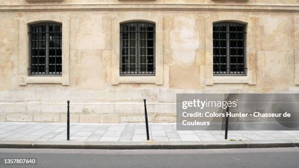 stone wall and sidewalk with windows and clean street in paris - sarjeta - fotografias e filmes do acervo