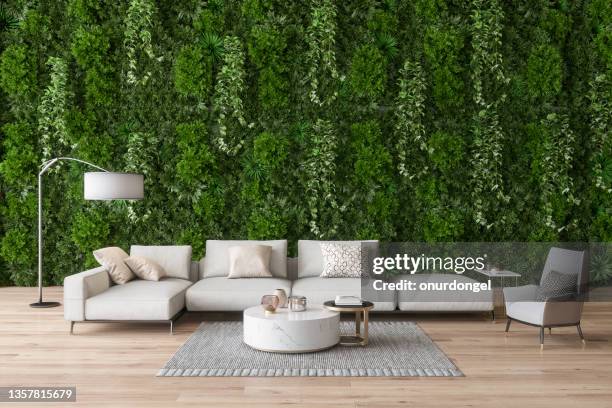 green living room with armchair, corner sofa, vertical garden and parquet floor - loungeroom stockfoto's en -beelden