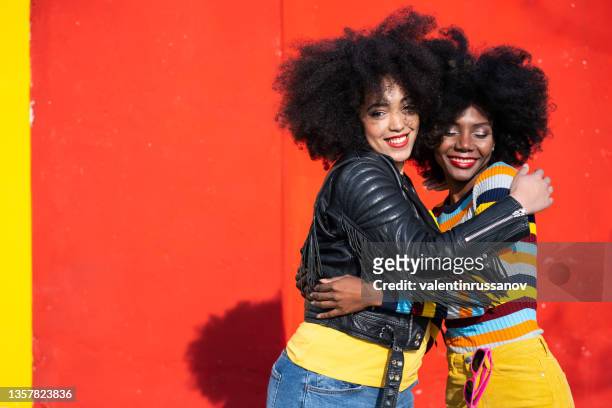 cheerful afro women standing together and smiling on colorful backgraund - afroamerikansk kultur bildbanksfoton och bilder