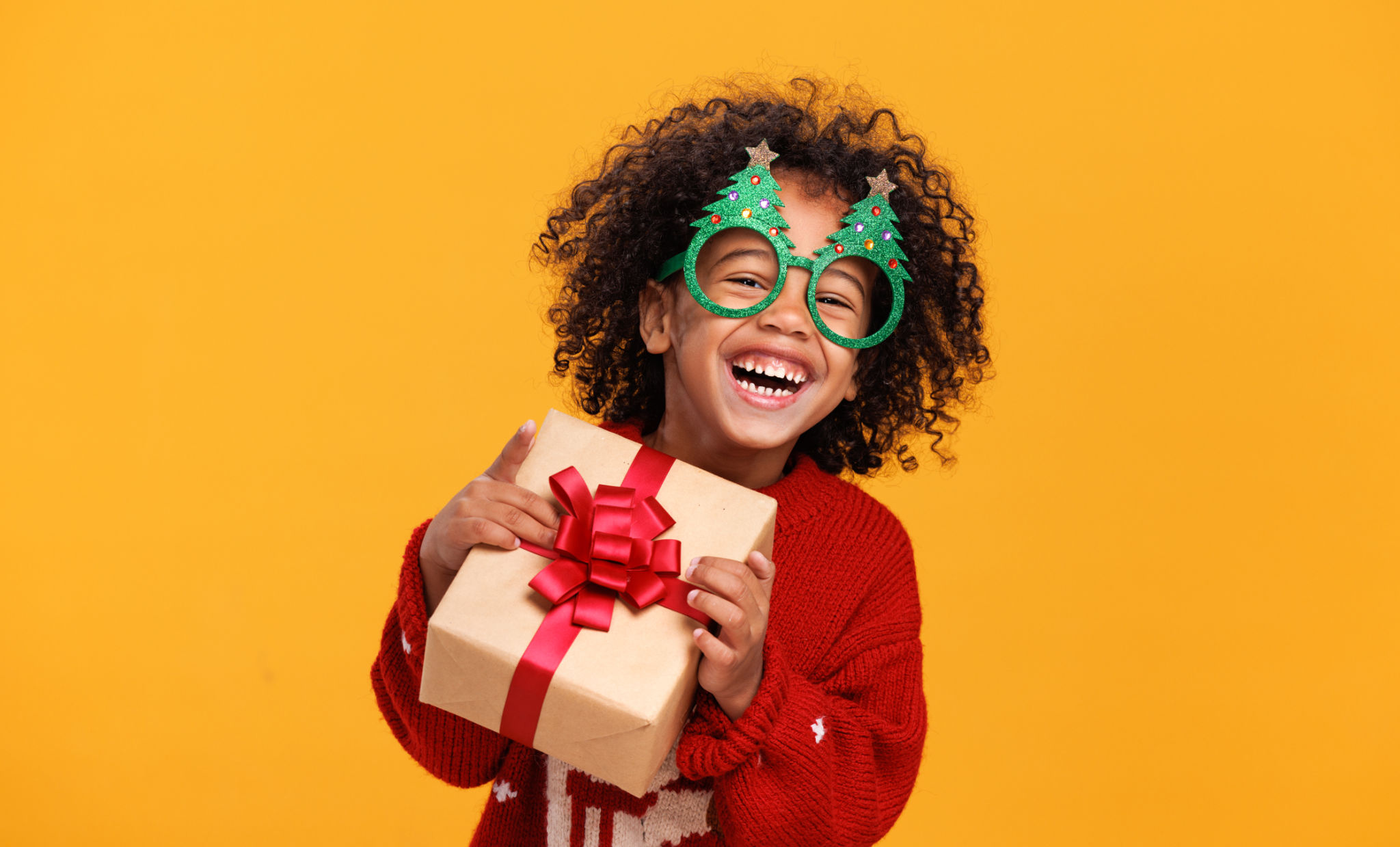 Happy little african american boy wearing funny glasses in form of Christmas trees with xmas gift Happy little african american boy wearing funny glasses in form of Christmas trees with xmas gift