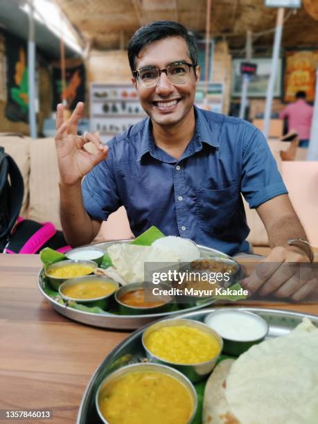 man eating food plate full of indian dishes - indian restaurant stock pictures, royalty-free photos & images