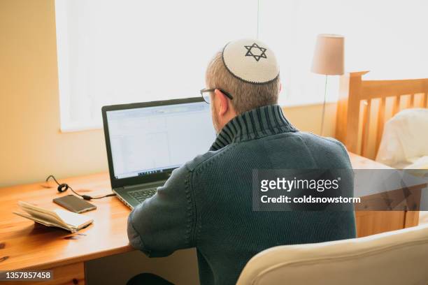 jüdischer mann mit totenkopfmütze, der von zu hause aus arbeitet - jewish people stock-fotos und bilder
