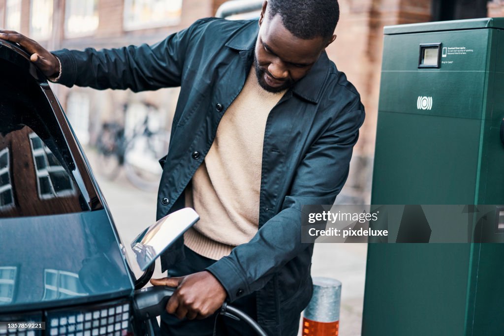 Cropped shot of a handsome young man recharging his electric car at a gas station