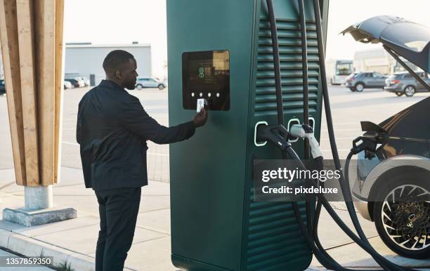 cropped shot of a handsome young man recharging his electric car at a gas station - car nfc stock pictures, royalty-free photos & images