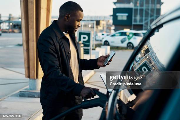 cropped shot of a handsome young man recharging his electric car at a gas station - bensinstation bildbanksfoton och bilder