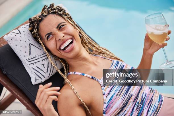 laughing young woman in a swimsuit drinking a cocktail next to a pool - poolside stock pictures, royalty-free photos & images