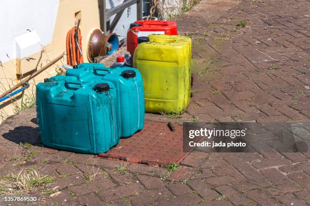 put four plastic jerry can in various colors on the street as waste - galón fotografías e imágenes de stock