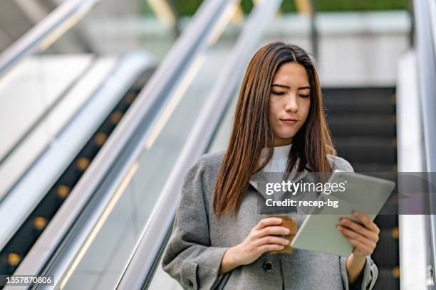 mixed-race businesswoman using digital-tablet while commuting in city - center for asian american media stock pictures, royalty-free photos & images