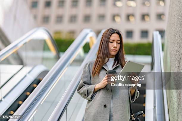 mixed-race businesswoman using digital-tablet while commuting in city - center for asian american media stock pictures, royalty-free photos & images