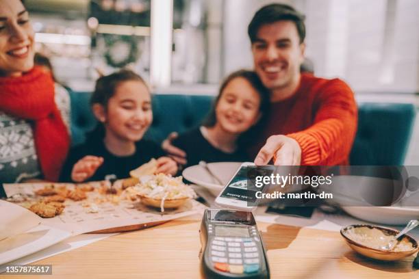 family in restaurant paying contactless - paying for dinner imagens e fotografias de stock