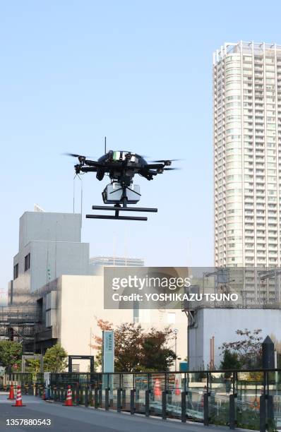 Drone à six rotors PF2 du fabricant japonais ACSL en vol transportant une boîte contenant des repas chauds pour un test de livraison de nourriture...