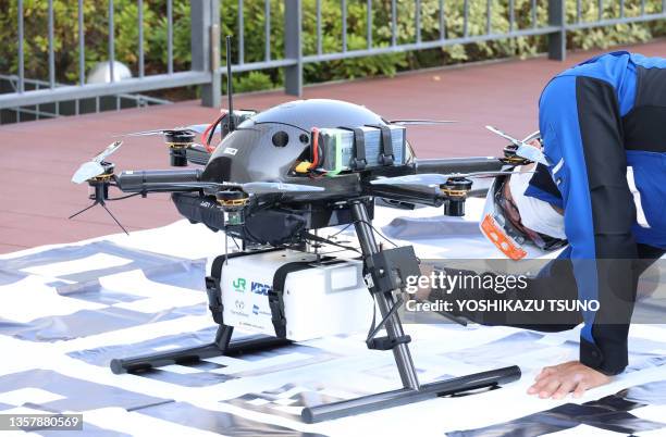 Ingénieur du fabricant de drones japonais ACSL plaçant une boîte contenant des plats chauds à bord du drone à six rotors PF2 de l'entreprise pour un...