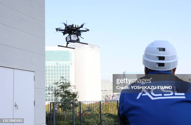 Drone à six rotors PF2 du fabricant japonais ACSL en vol transportant une boîte contenant des repas chauds pour un test de livraison de nourriture...