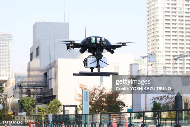 Drone à six rotors PF2 du fabricant japonais ACSL en vol transportant une boîte contenant des repas chauds pour un test de livraison de nourriture...