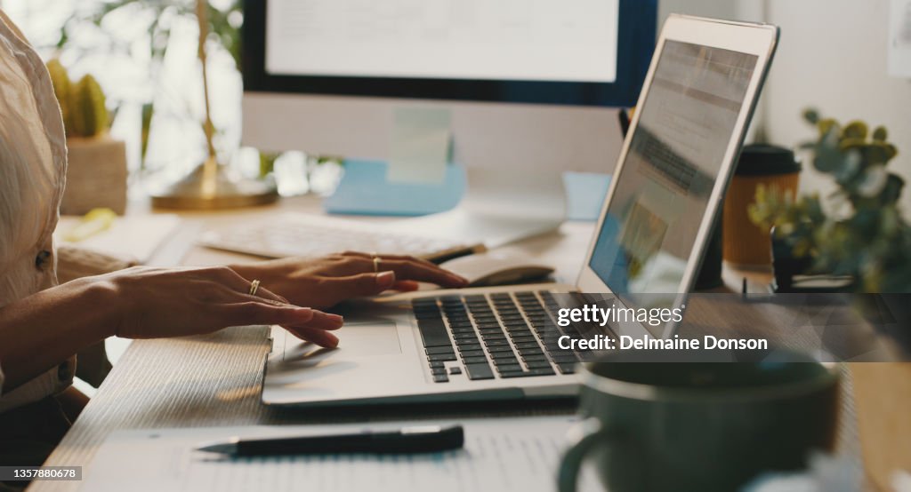 Zugeschnittene Aufnahme einer unkenntlichen Geschäftsfrau, die alleine sitzt und ihren Laptop benutzt, während sie von zu Hause aus arbeitet