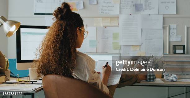 shot of an unrecognisable businesswoman sitting alone in her home office and making notes - curly hair back stock pictures, royalty-free photos & images