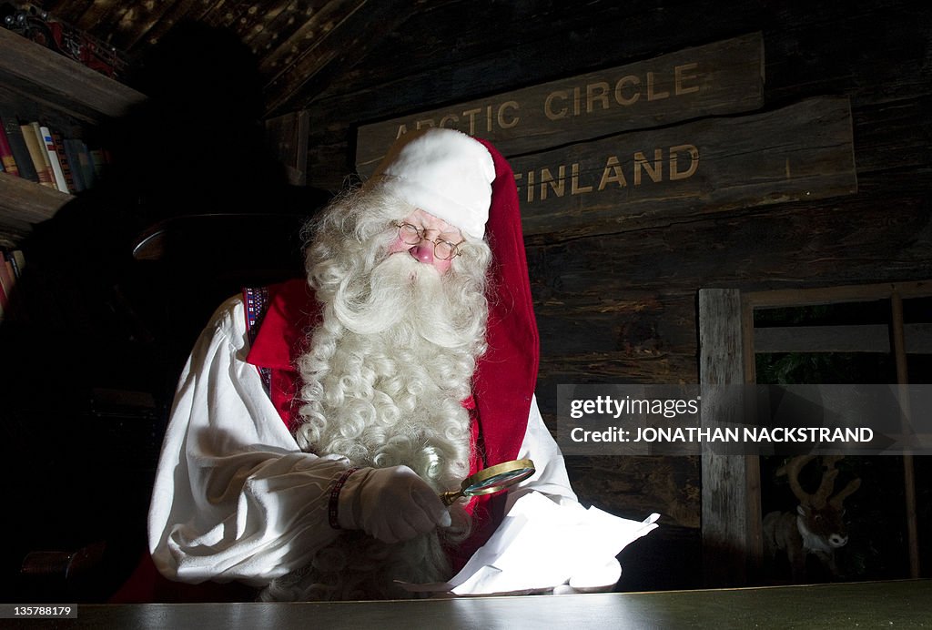Santa Claus reads letters at his desk in