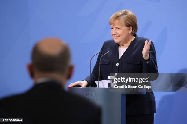 Former German Chancellor Angela Merkel speaks as new Chancellor Olaf Scholz listens during the official transfer of office at the Chancellery on...