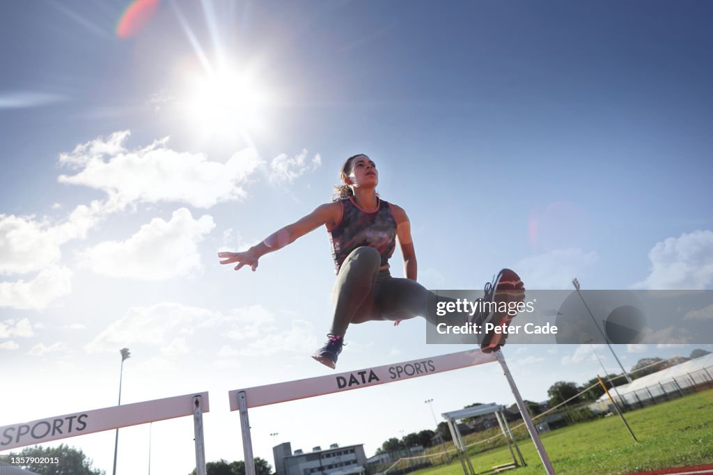 Woman jumping over hurdle