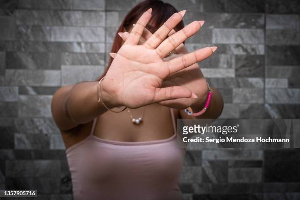 young latino woman looking at the camera and gesturing to stop - 性的虐待 ストックフォトと画像