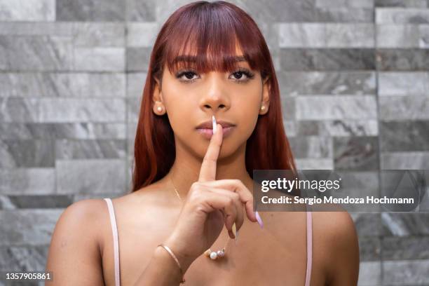 young latino woman looking at the camera with a finger on her lips, asking for quiet, silence - finger on lips bildbanksfoton och bilder