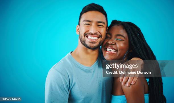 shot of a young couple posing together against a blue background - couple coloured background stock pictures, royalty-free photos & images