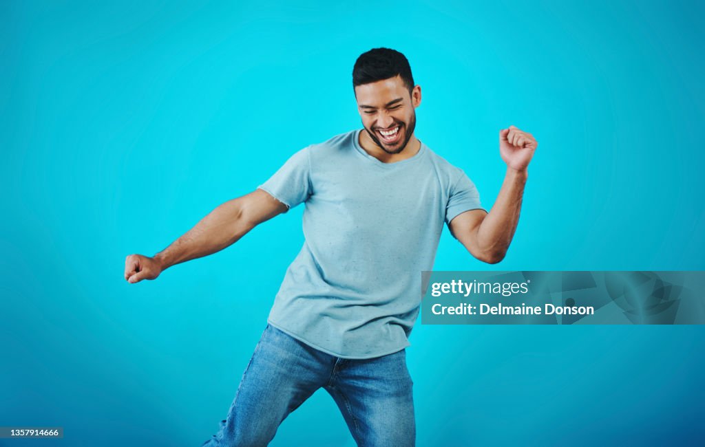 Aufnahme eines gutaussehenden jungen Mannes, der vor blauem Hintergrund tanzt