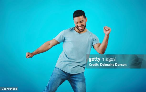 foto de un apuesto joven bailando sobre un fondo azul - celebración fotografías e imágenes de stock