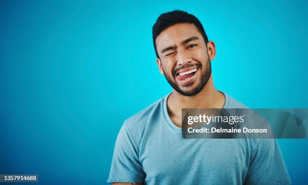 scatto di un bel giovane in posa su uno sfondo blu - human tongue foto e immagini stock