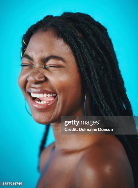 shot of a beautiful young woman laughing against a blue background - eyelid stock pictures, royalty-free photos & images