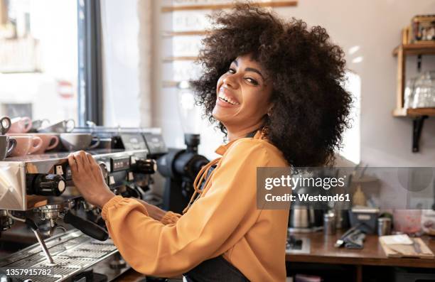 waitress with afro hairstyle at coffee machine in cafe - espressomaschine stock-fotos und bilder