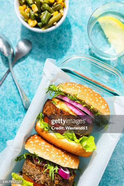 rice burgers in container by salad and glass on table - veggie burger stock pictures, royalty-free photos & images