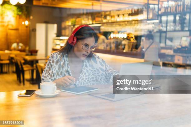 young freelancer working on graphics tablet and laptop at cafe - ipad kopfhörer stock-fotos und bilder