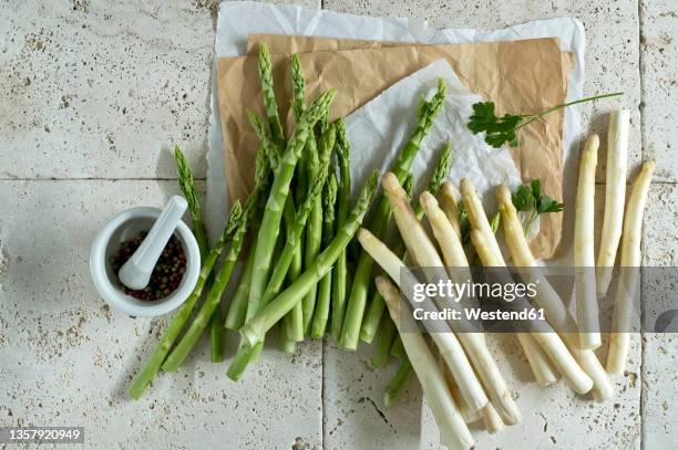 studio shot of mortar and pestle, parsley and asparagus stalks lying on stone surface - asparagus stock pictures, royalty-free photos & images