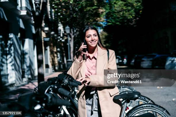 businesswoman talking on mobile phone at bicycle parking station - bicycle parking station stock pictures, royalty-free photos & images