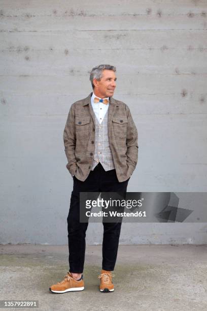 man standing in front of wall with hands in pockets - chaqueta de ante fotografías e imágenes de stock