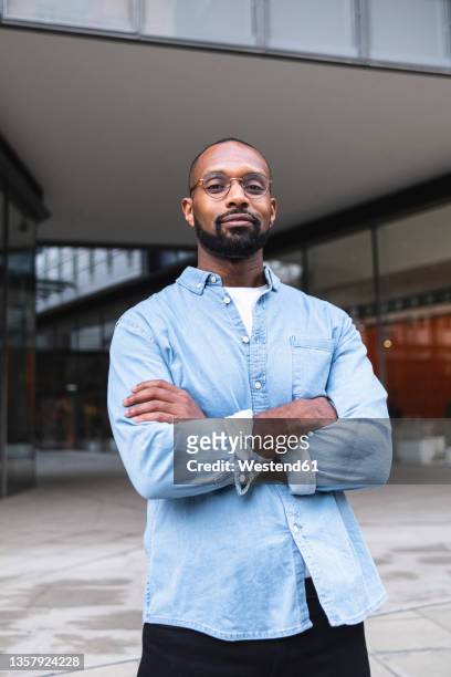 man in casual clothing standing with arms crossed near buildings - man arms crossed stock pictures, royalty-free photos & images