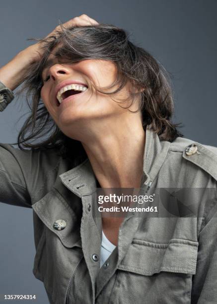 carefree woman with head in hand against gray background - beautiful mature woman stock pictures, royalty-free photos & images