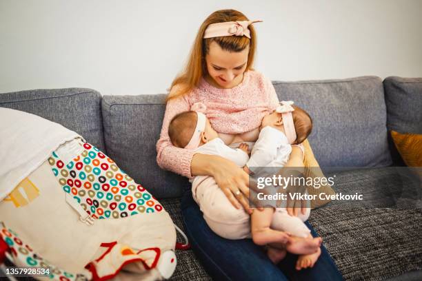 madre joven amamantando a sus bebés recién nacidos - twin fotografías e imágenes de stock