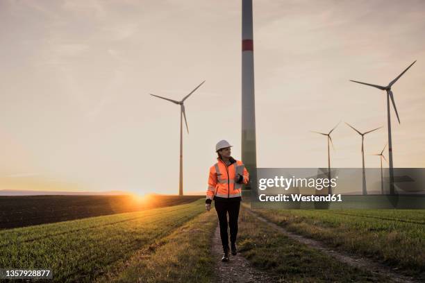 engineer with tablet pc walking on footpath at wind park - career path stock pictures, royalty-free photos & images