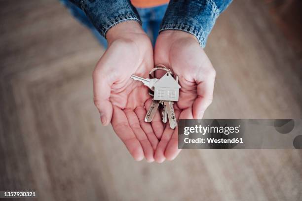 woman with hands cupped holding house keys at home - hohle hände stock-fotos und bilder