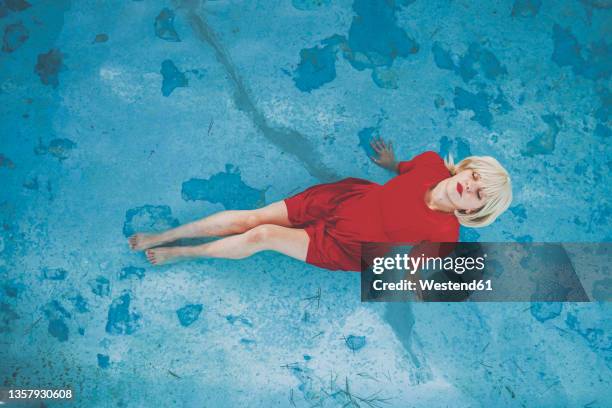 woman with eyes closed relaxing in swimming pool - red dress ストックフォトと画像