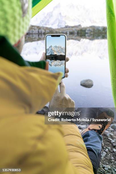 personal perspective of man photographing mont blanc with smartphone - lake chesery stockfoto's en -beelden