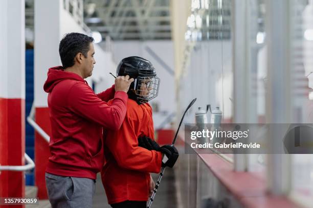père aidant son fils à se préparer à l’entraînement - hockey photos et images de collection