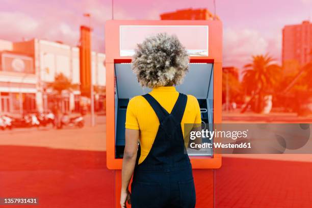 woman with afro hairstyle using red atm machine - atm 個照片及圖片檔