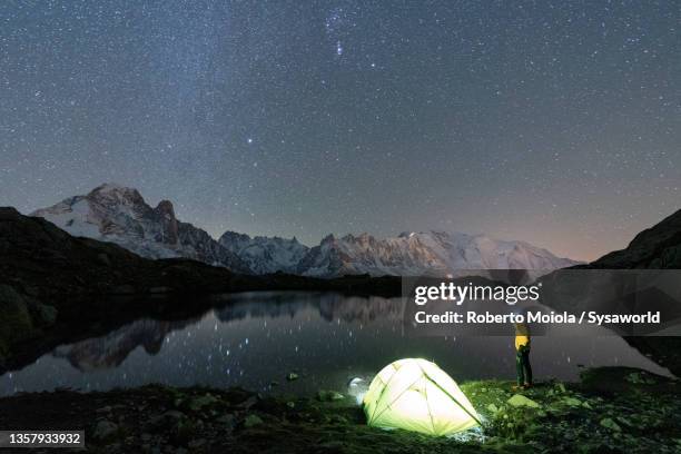 person with tent admiring stars over mont blanc from chesery lake - lake chesery stockfoto's en -beelden
